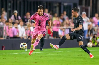 Soccer player Lionel Messi plays against Nashville SC defender Daniel Lovitz on a field during a professional game.