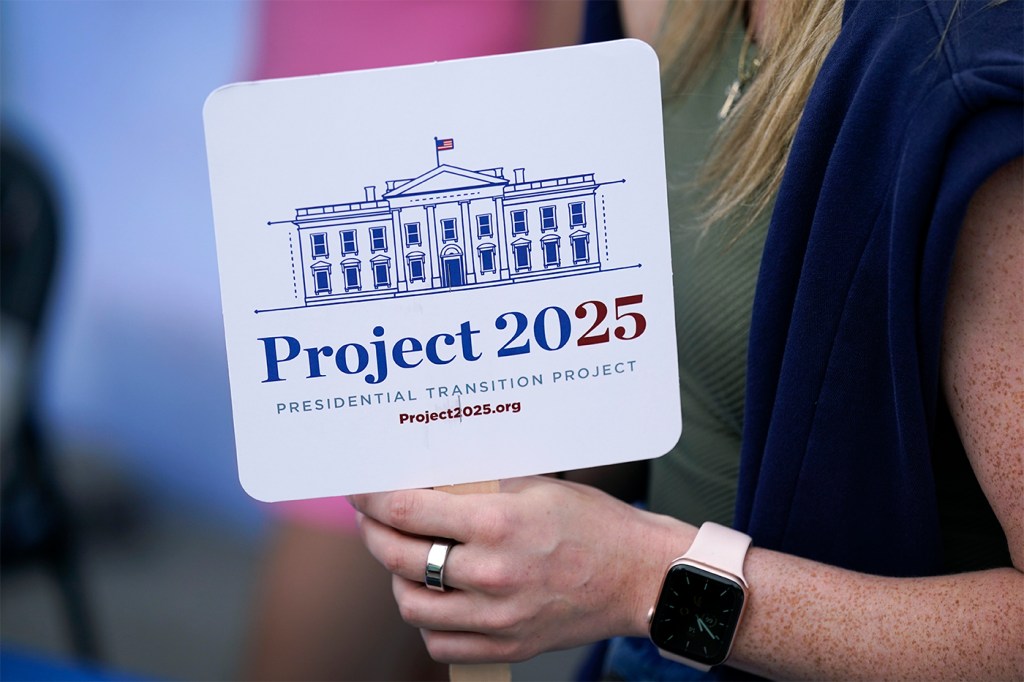 Person holds up a Project 2025 sign with a drawing of the White House on it.