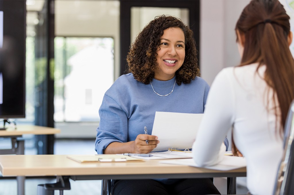 Staffing agency worker reviews a paper while helping a client.