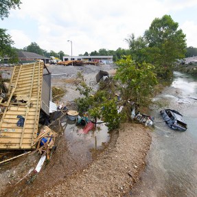 After a storm, a flooded road has displaced cars and trees.