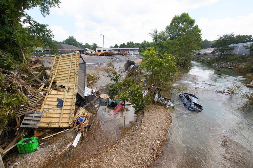 After a storm, a flooded road has displaced cars and trees.