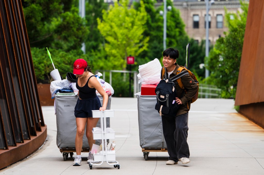 Two people carry moving materials across a bridge.