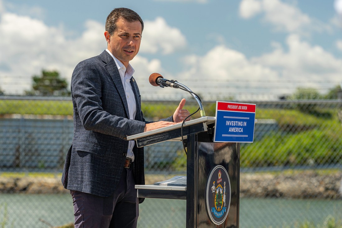 US Secretary of Transportation Pete Buttigieg speaking at a podium in Portland.