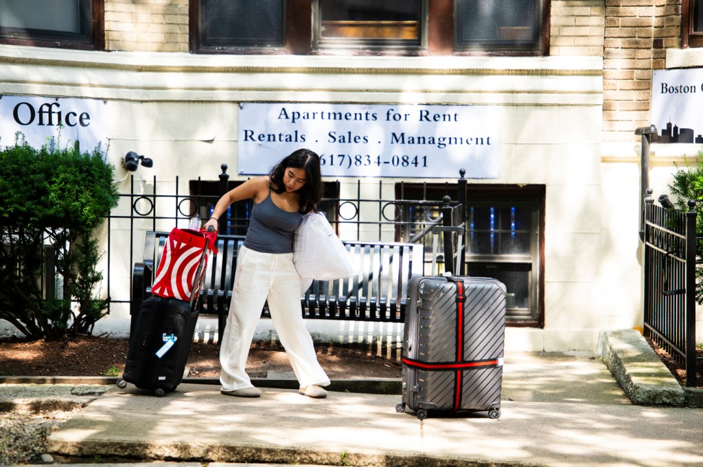 A student is pulling luggage as they move into Boston housing.