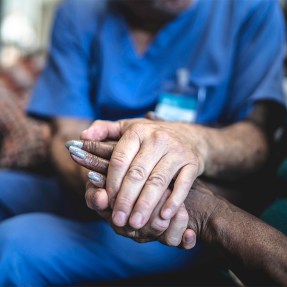 A nurse holding the hands of a patient.