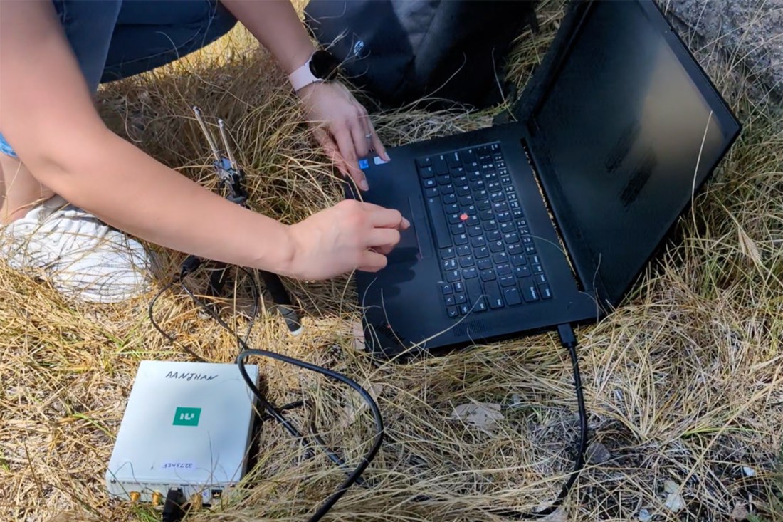 A person working on a laptop in the grass.