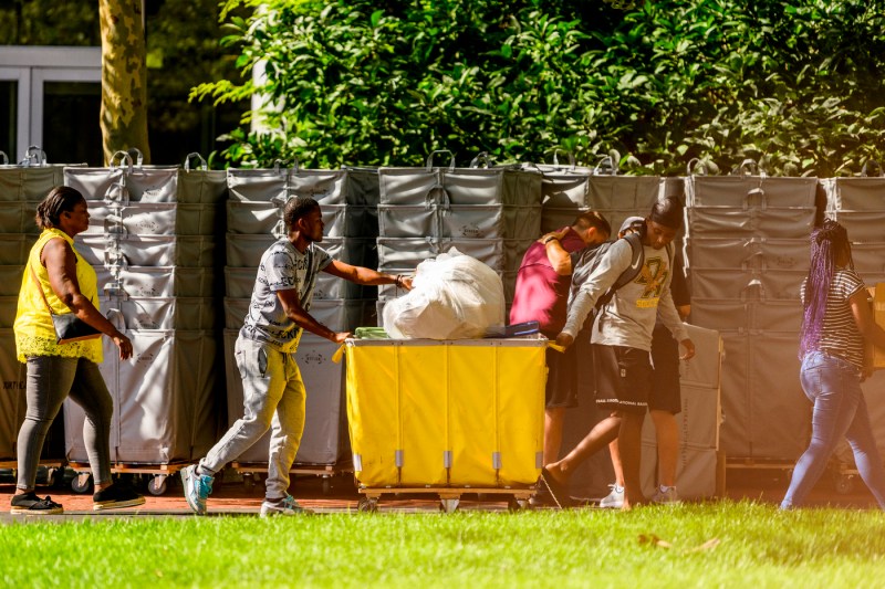 Students push a rolling bin full of their things