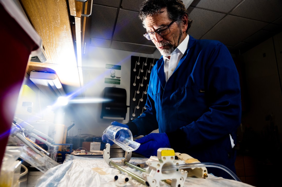 Craig Ferris standing at a lab table working with a tube of plastic. 