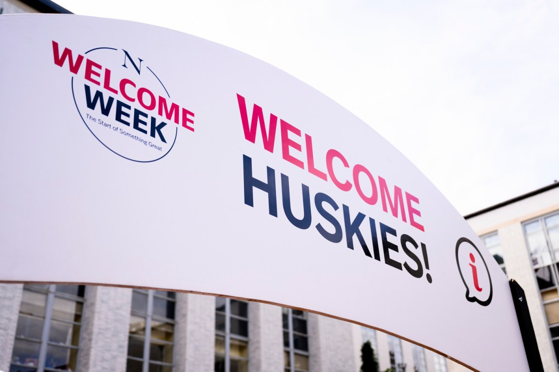 A white sign with red and black text: "Welcome Week, Welcome Huskies."