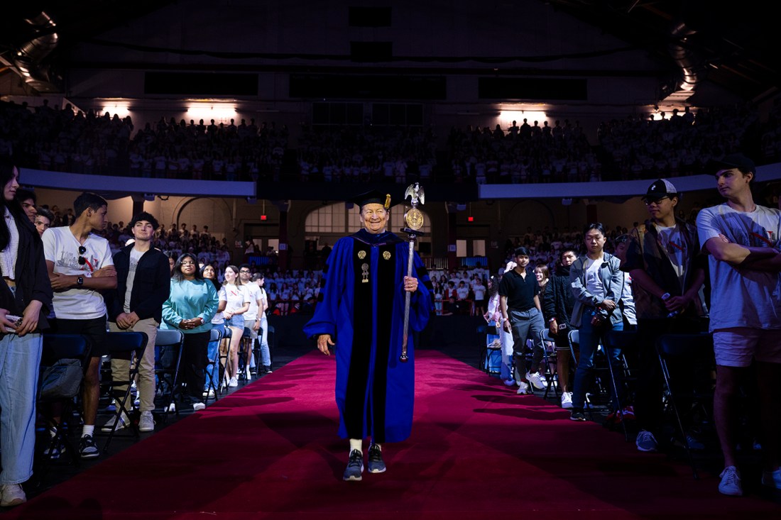 Mary Jo Ondrechen dressed in regalia holding the ornamental staff at Convocation.