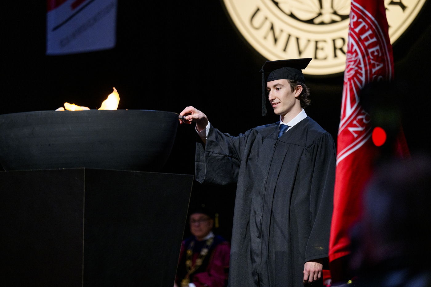 A student lighting a torch at convocation.