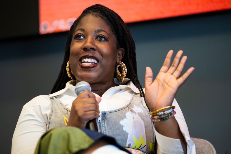 Adebukola Ajao speaking into a microphone while gesturing with one hand. 