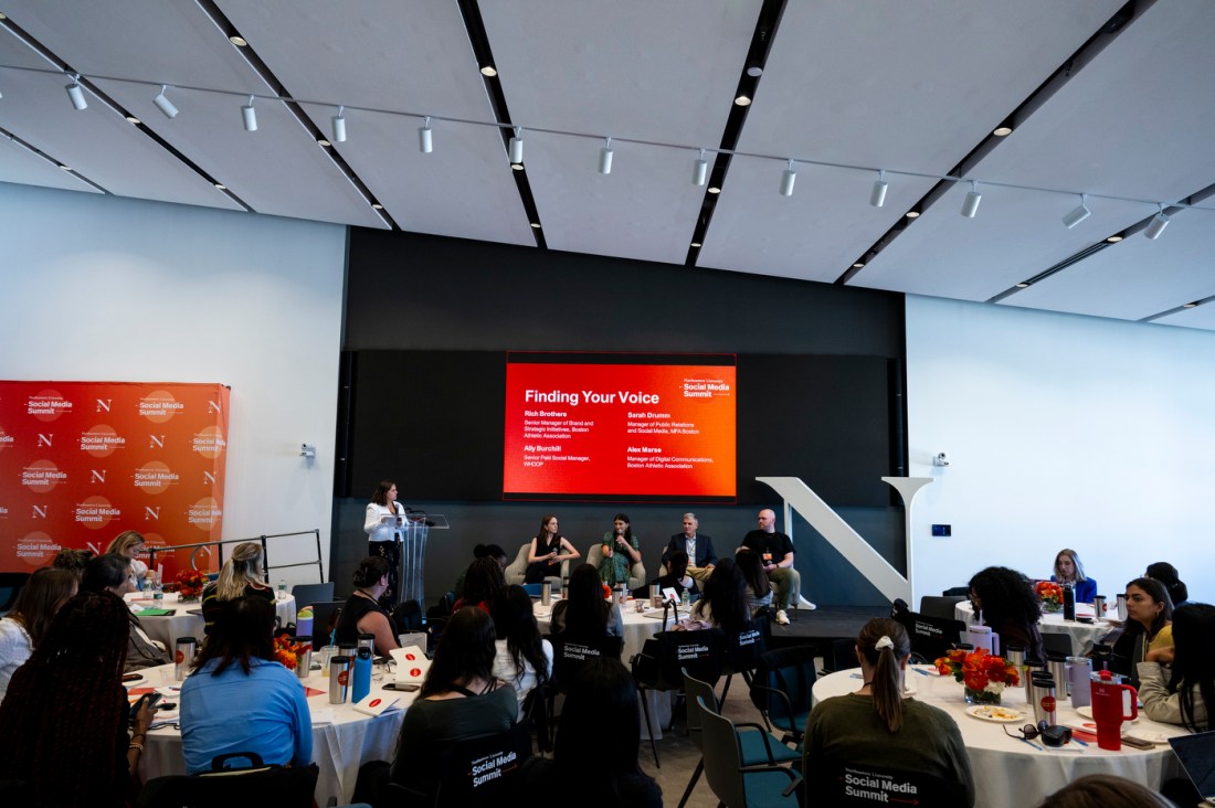 Sarah Drumm, Ally Burchill, Rich Brothers, and Alex Marse sitting on stage under a TV that says 'Finding Your Voice' on an orange background. Fernanda Hurtado-Ortiz is standing to one side at a podium. 