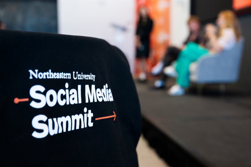 A black tote bag with 'Northeastern Social Media Summit' on it in white text.