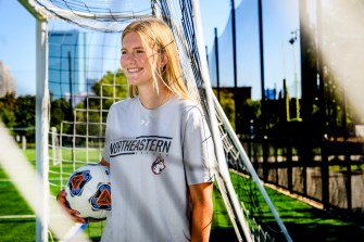 Jessie Hunt standing next to a soccer goal with a soccer ball tucked under her arm.