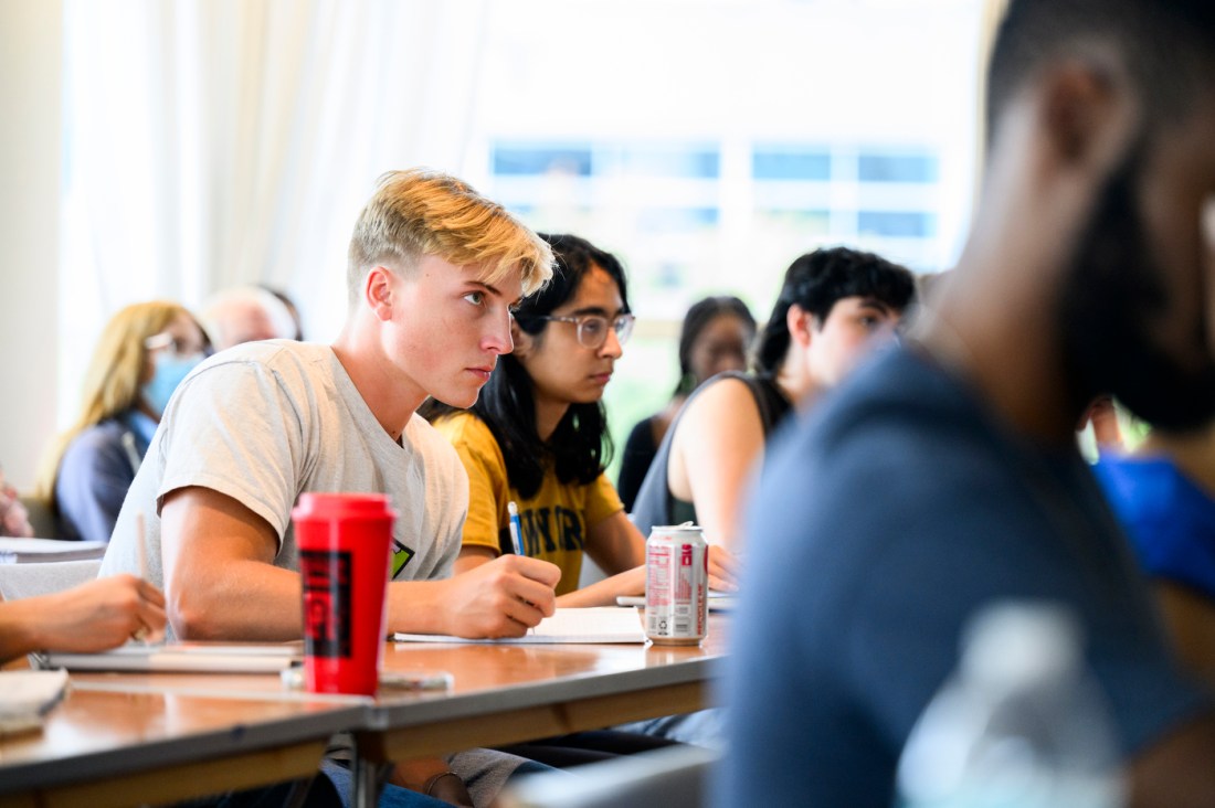 A student taking notes on a notepad with a can of Diet Coke open in front of them.