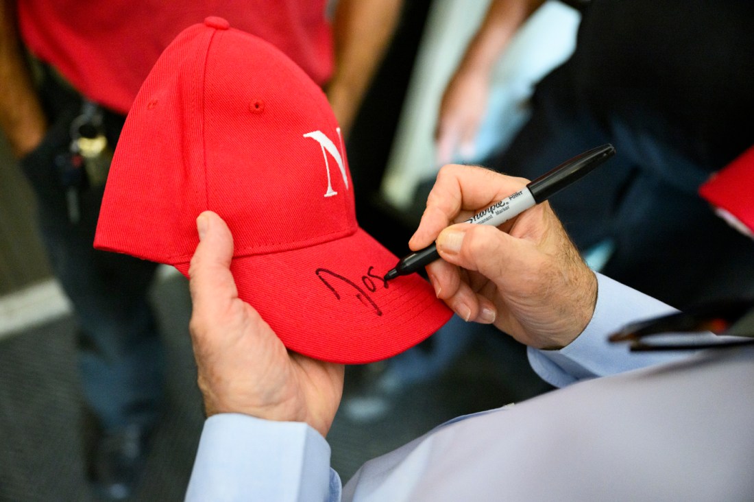 President Aoun signing a red baseball cap. 