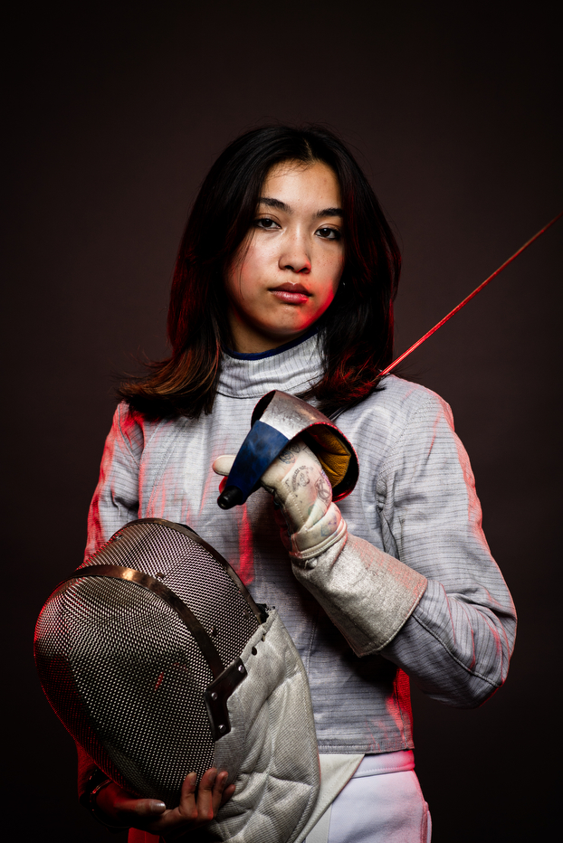 Sabrina Balmaseda posing in fencing gear with a sword over her shoulder.