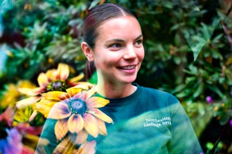 Headshot of Kelly Young standing outside with yellow flowers overlayed.