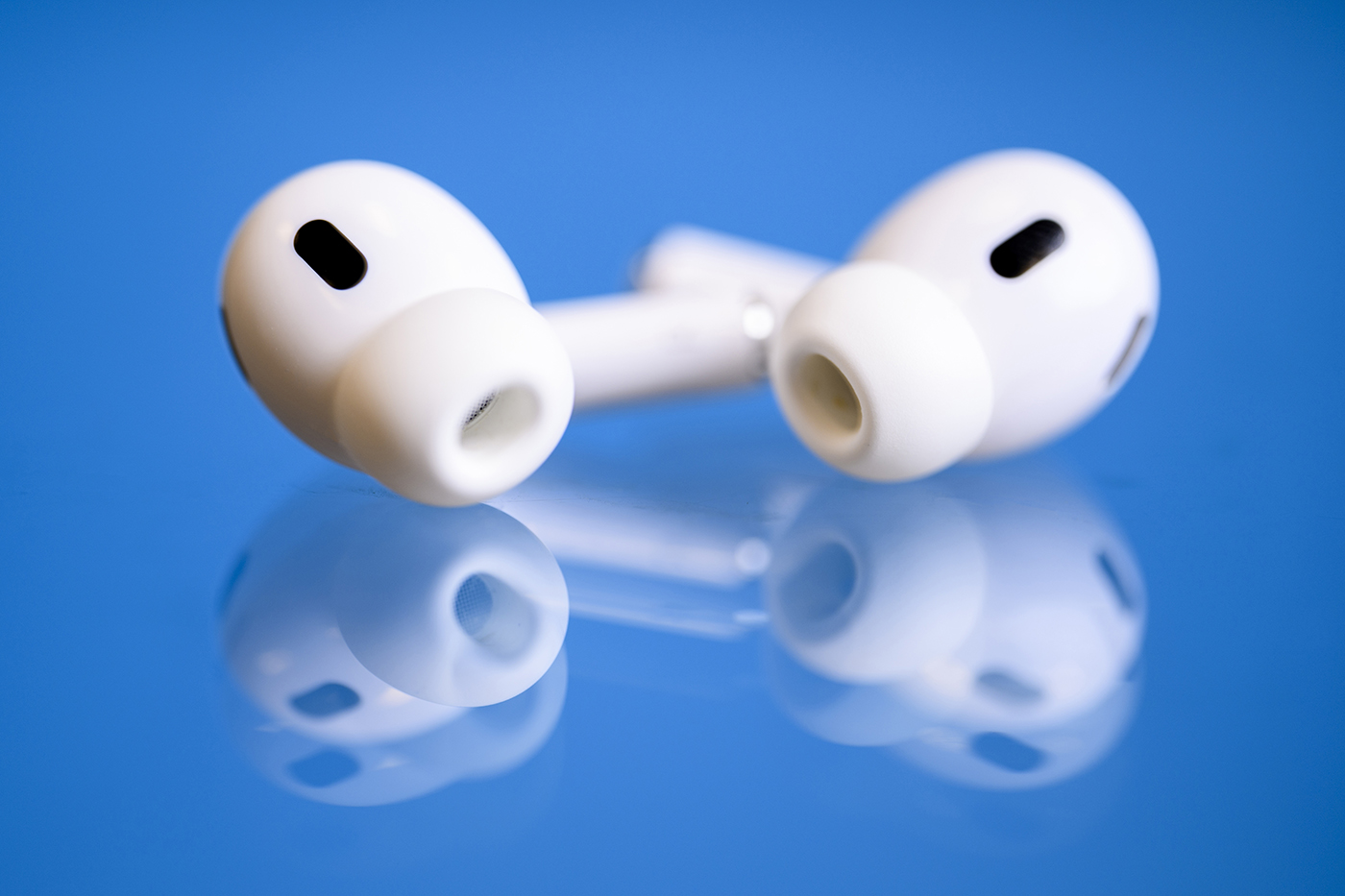 Apple Airpods laying on a blue surface.