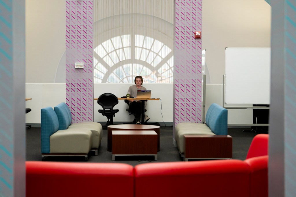 A person studying sits between two purple columns in a study area.