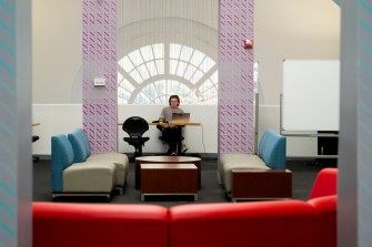 A person studying sits between two purple columns in a study area.