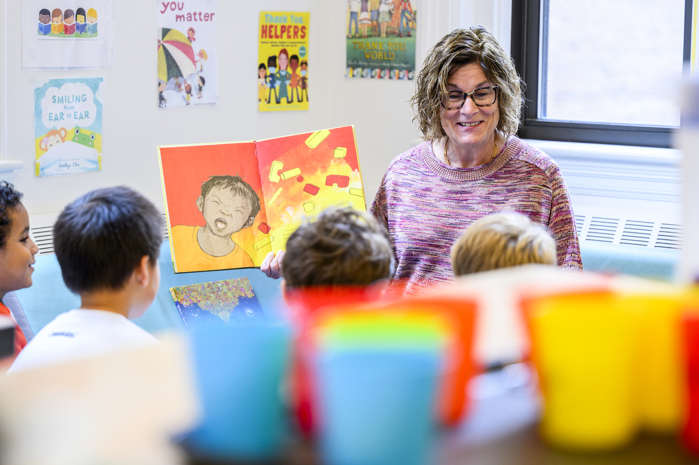 Laa Ann Burdick readin ga kids book to a group of children gathered around her.