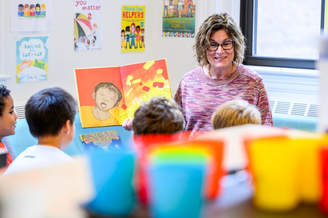 Laa Ann Burdick readin ga kids book to a group of children gathered around her.