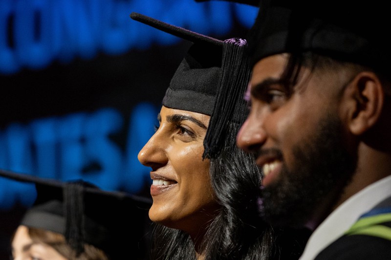 Two graduates wearing caps smiling.