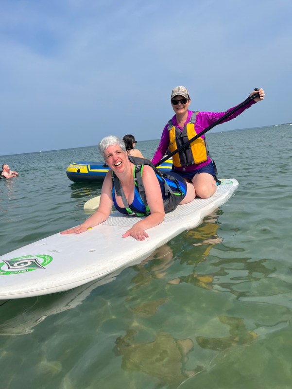 Kim Ho on a paddle board with a person with disabilities. 