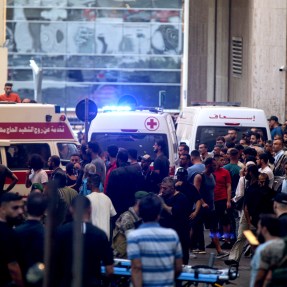 Ambulances with their lights on next to a crowd of people in Lebanon.