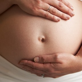 A pregnant person holding their stomach.