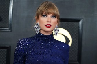 Taylor Swift at the Grammy's wearing a blue sparkling dress and large silver and blue diamond-shaped earrings.