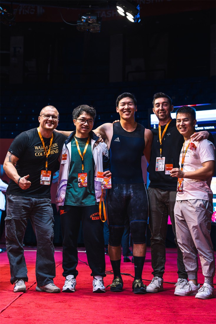 Matthew Tung posing with others at a weightlifting competition.