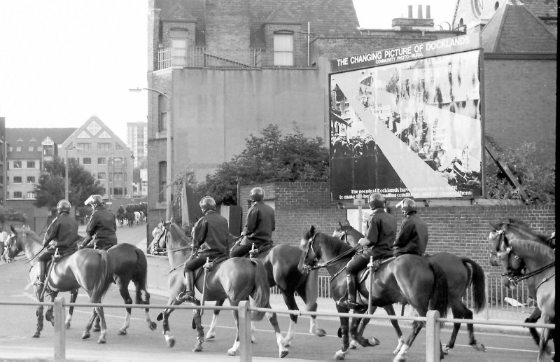 A black and white photo of police officers on horses.