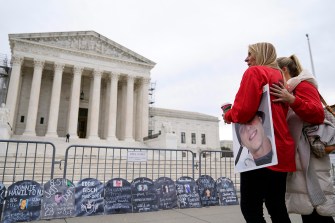 Two people standing arm in arm outside of the Supreme Court.