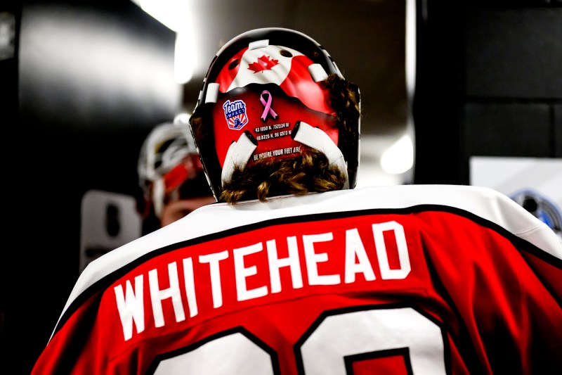 A person wearing a hockey uniform with a name embroidered in white on the back, "WHITEHEAD."