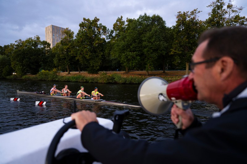 A person speaks into a blowhorn while traveling down a river on a boat.