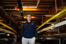 Portrait of Joe Wilhelm standing inside a boathouse.