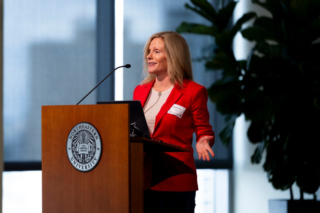 A woman wearin ga red blazer speaking at the Women of the Cloud College Tour.