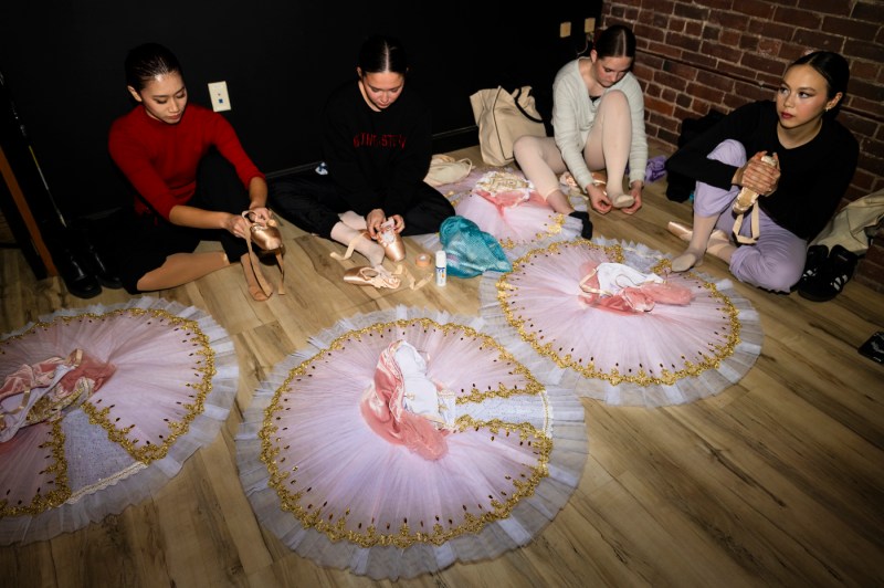 Ballet dancers putting on their pointe shoes.