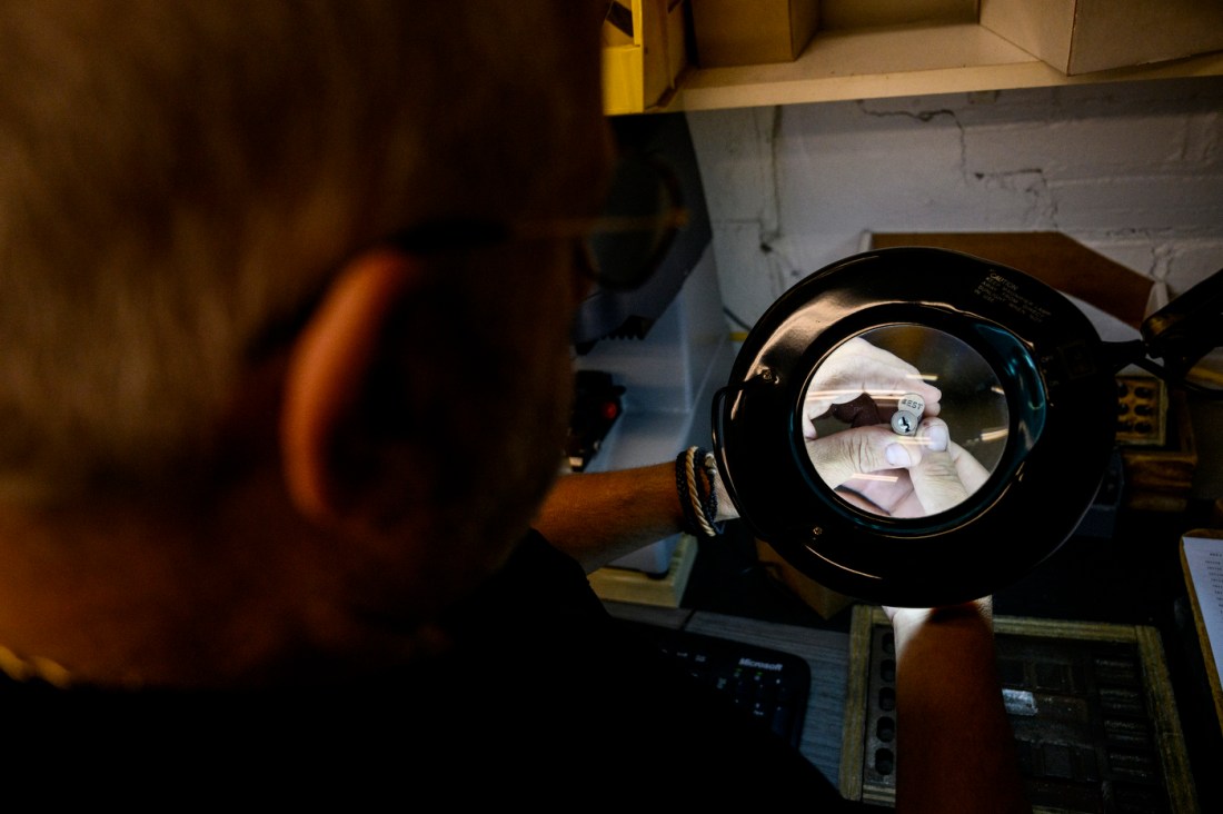 A locksmith working with tools in a workshop filled with mechanical equipment and supplies.