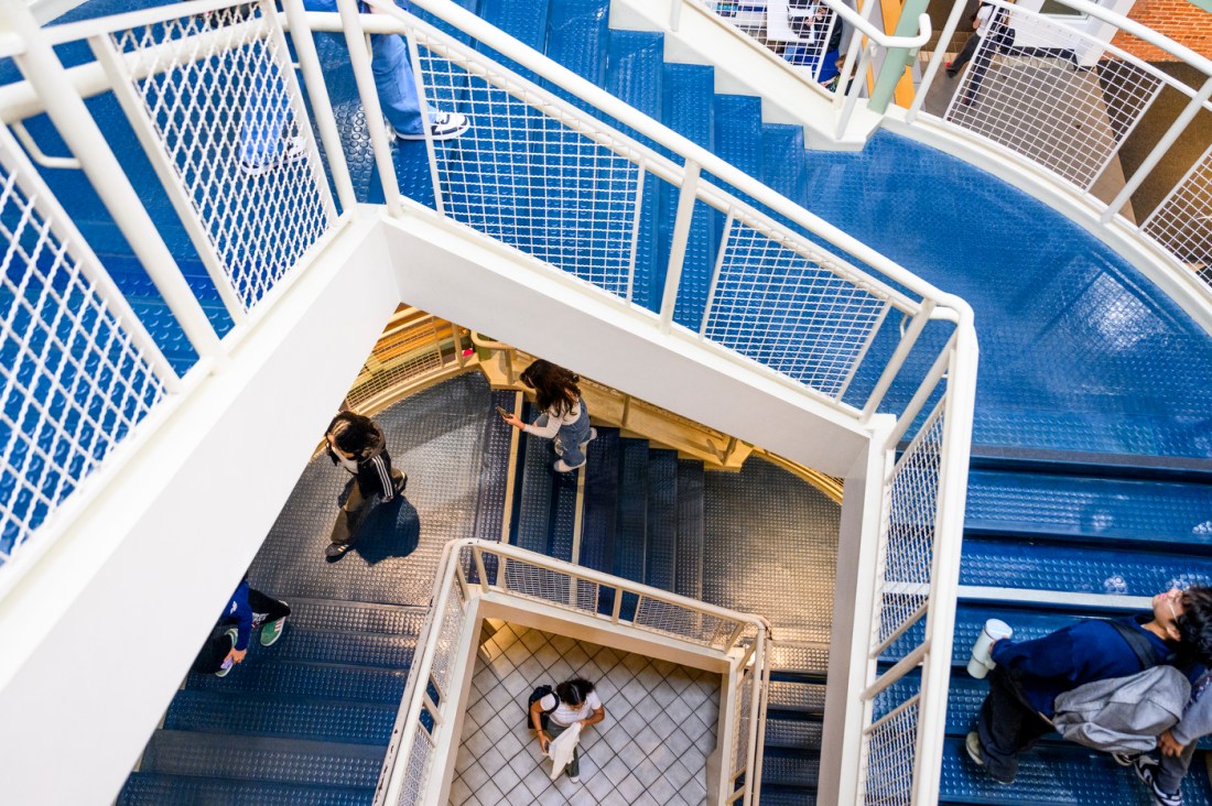 A top-down view of students on a blue and white spiral stairwell.