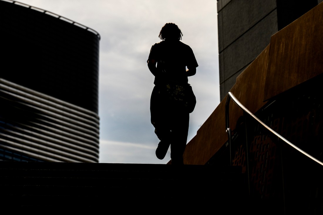 A silhouette of a student walking across a campus bridge.