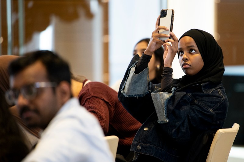 A person holds a phone to record a presentation about energy efficient solutions. 