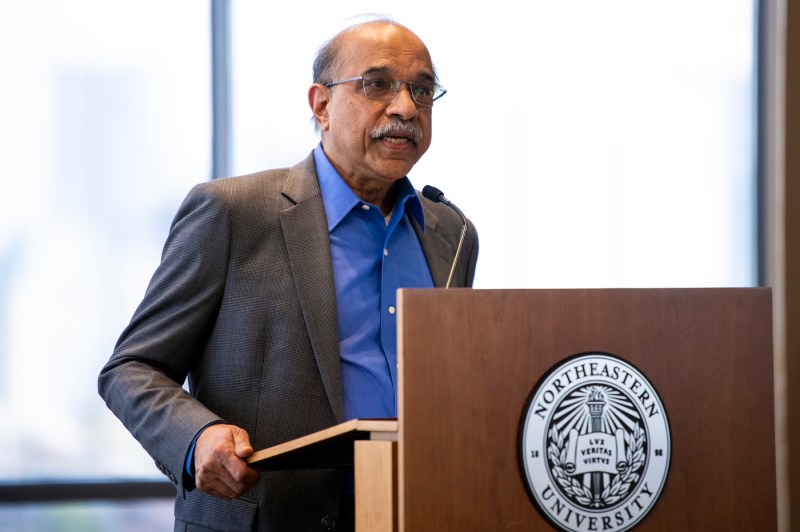 A person wearing a suit speaks at a podium. 