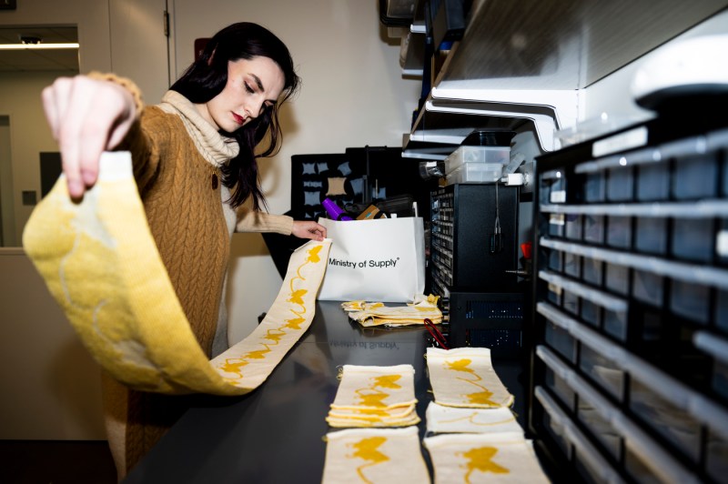 Megan Hoffman holding up the pattern of butterflies used to knit Dean Beth Mynatt's shawl. 