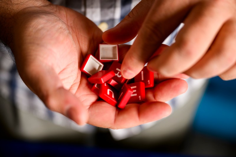 Bradley Whitmarsh holding red scrabble tiles in his hand.