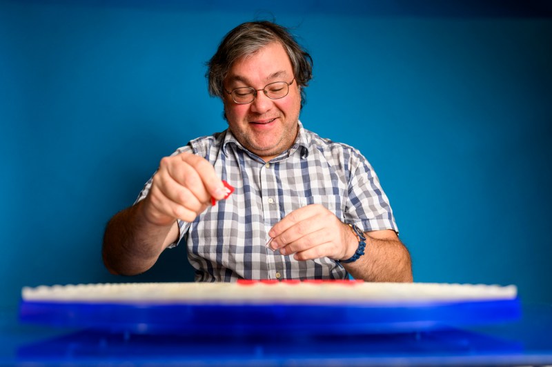 Bradley Whitmarsh placing scrabble tiles on a board.