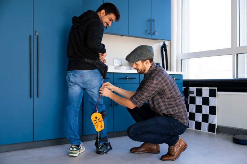 Max Shepherd works on an exoskeleton on Divyansh Gupta's leg.